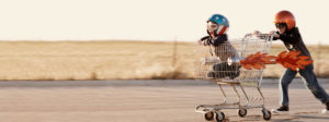 Two brothers acting like a shopping cart is their rocket.