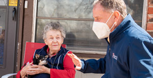 BVC chaplain sitting on a porch with a resident and her small dog