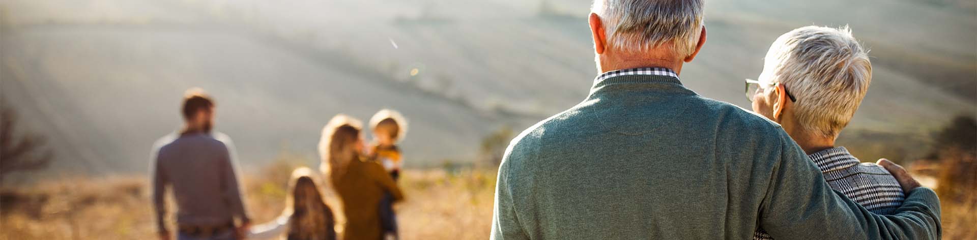 Photo of Grandparents looking on to their children and grandchildren in a mountain valley