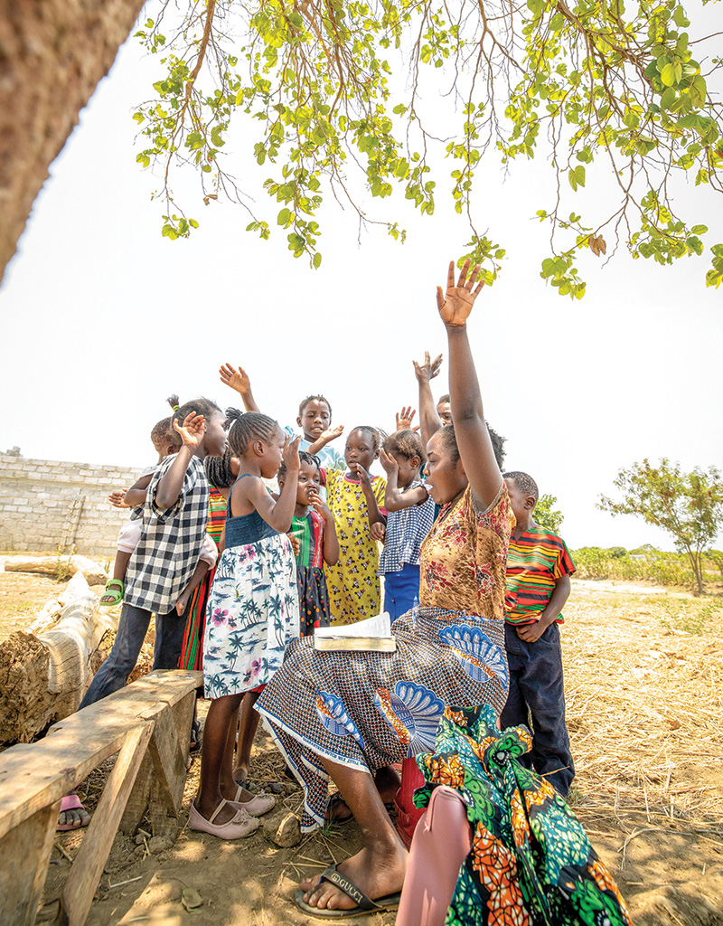 Woman teaching bible to kids under a tree