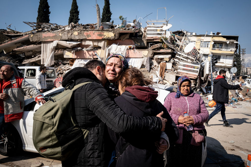 7.8 earthquake in Türkiye Image of family hugging in front of destroyed building.