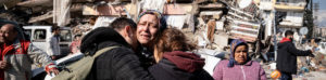 Family hugging next to earthquake-damaged building