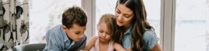 Mom and kids reading at the kitchen table.