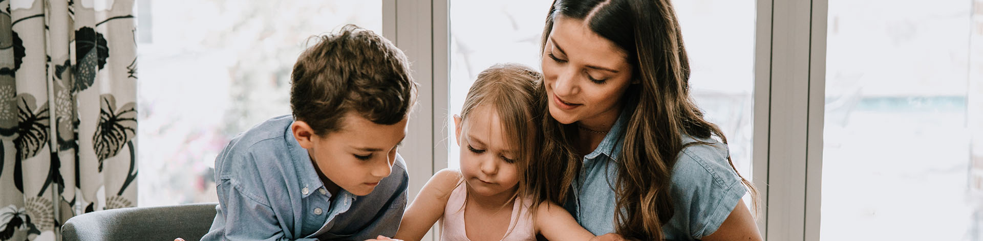 Mom and kids reading at the kitchen table.