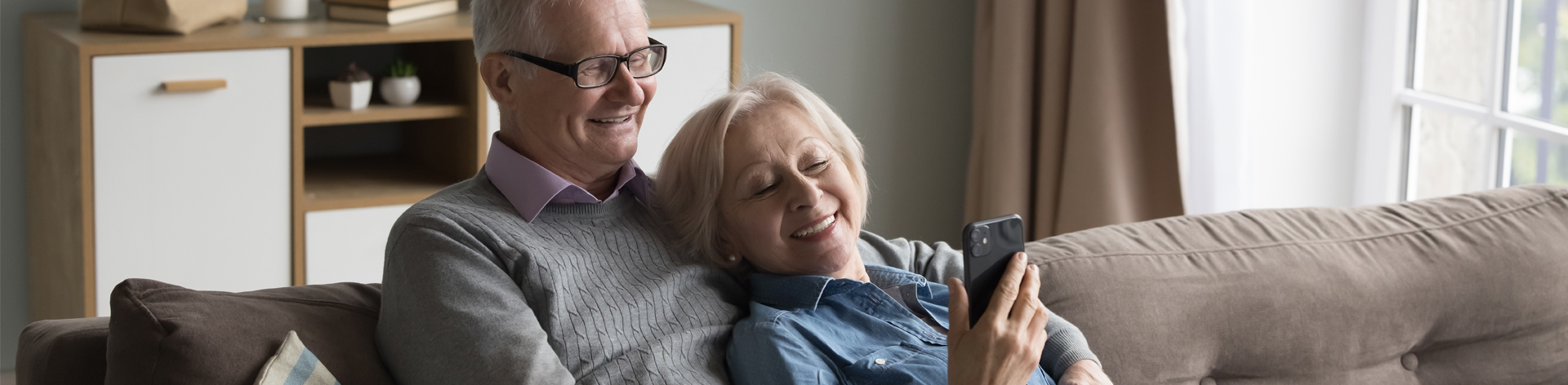 Senior couple on couch looking at cell phone